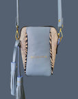 Blue crossbody bag with zebra pattern and tassel on a dark gray background