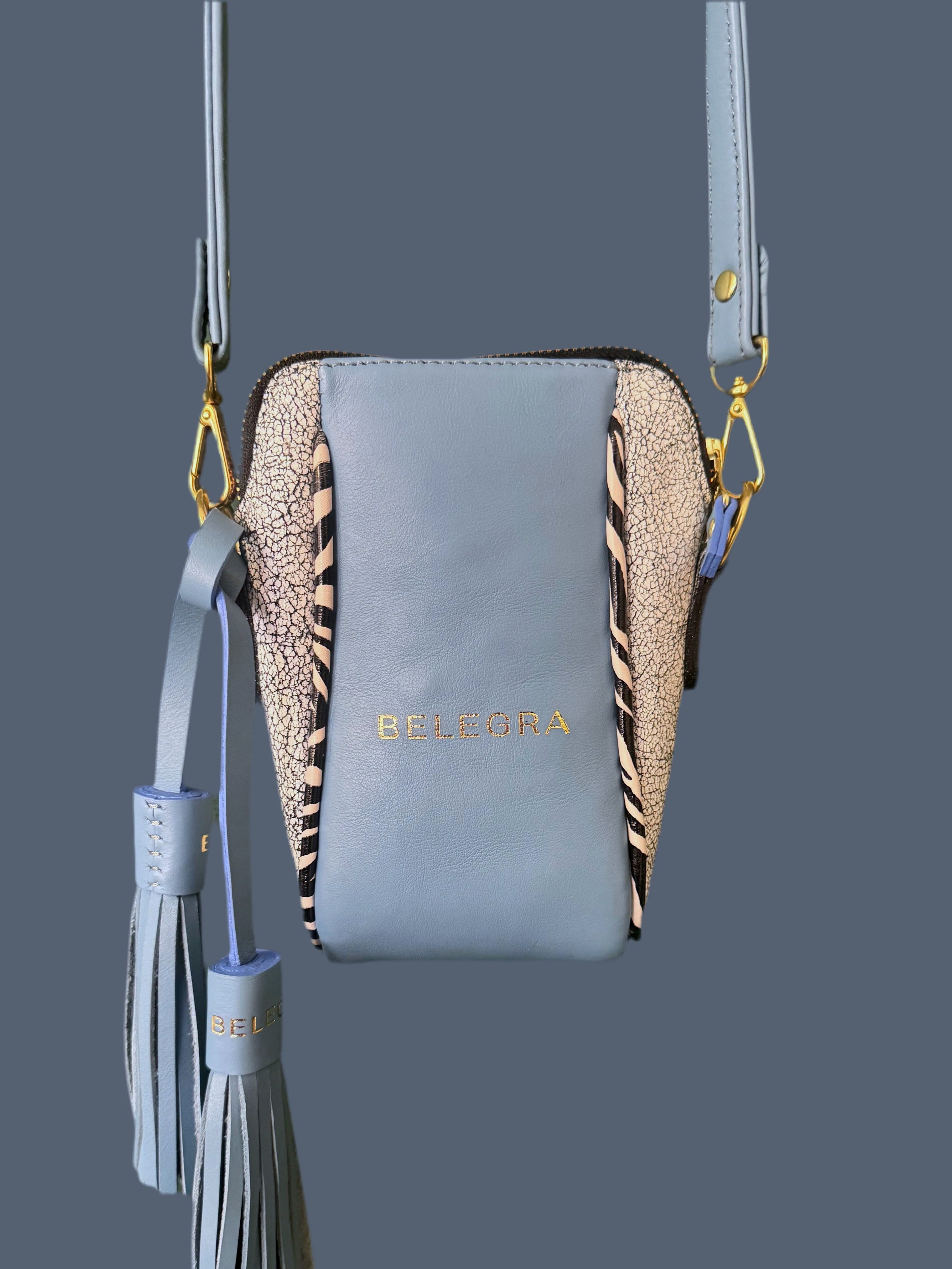 Blue crossbody bag with zebra pattern and tassel on a dark gray background